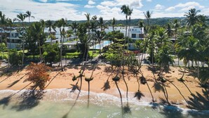 Un hotel sulla spiaggia con palme, una piscina e vista sull'oceano.