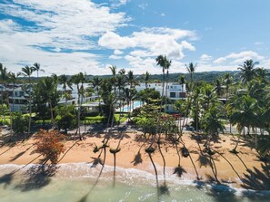 A beachfront hotel with palm trees, a pool, and a view of the ocean. - Modern 2BR Condo w/ Beach Views • Sol de Arena A6 (Las Terrenas)