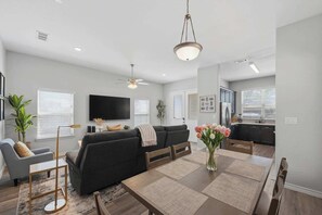 Ein modernes Wohnzimmer mit Sofa, Fernseher und Essbereich.