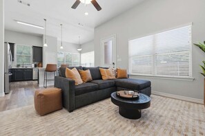 Ein modernes Wohnzimmer mit Ecksofa, Hocker und Couchtisch.