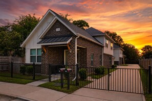 Ein zweistöckiges Haus mit Ziegelverkleidung, einer Veranda und einem schwarzen Metallzaun.