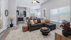 Un salon moderne avec un canapé d’angle, une table basse et un ventilateur de plafond.