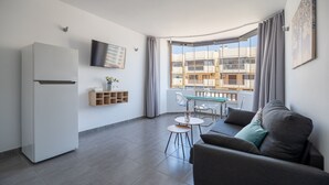Un appartamento moderno con cucina, sala da pranzo e soggiorno con divano e TV a parete.