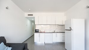 Una cucina moderna con mobili bianchi, lavastoviglie e frigorifero.