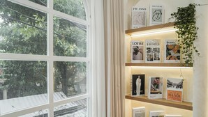 A bookshelf with books and a hanging plant. - Là Home - Stay Cozy, Stay Home Phú Nhuận (Ho Chi Minh City)