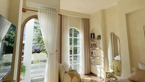 A bedroom with a bed, a TV, a window with curtains, a mirror, and a wall-mounted shelf. - Là Home - Stay Cozy, Stay Home Phú Nhuận (Ho Chi Minh City)