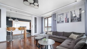 Una sala moderna con un sofá, dos mesas redondas y una zona de comedor con sillas.