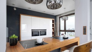 Una cocina moderna con encimera de madera, armarios blancos y vistas a la ciudad a través de una ventana.