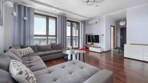 Una sala de estar moderna con un sofá modular, una mesa de centro redonda y un televisor de pantalla plana.