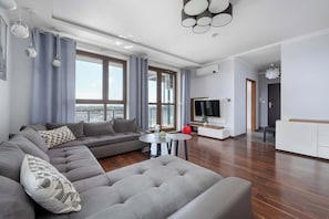 Ein modernes Wohnzimmer mit einer Eckcouch, einem runden Couchtisch und einem Flachbildfernseher.
