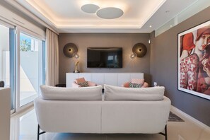 A modern living room with a sofa, a flat-screen TV, and a painting on the wall. - Rojales Poolside Apartment (Quesada)