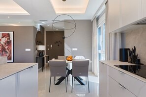 A modern kitchen with a dining area, a coffee machine, and a large window. - Rojales Poolside Apartment (Quesada)
