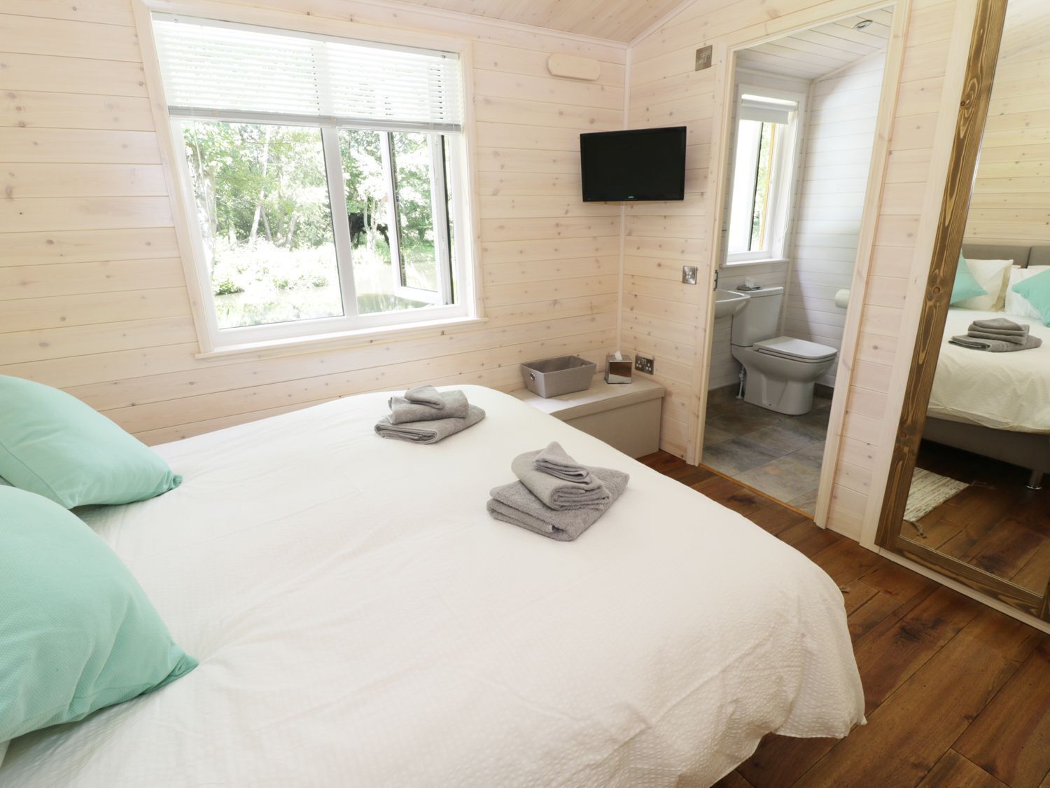 Une chambre avec un lit, une télévision, une fenêtre et une salle de bain.