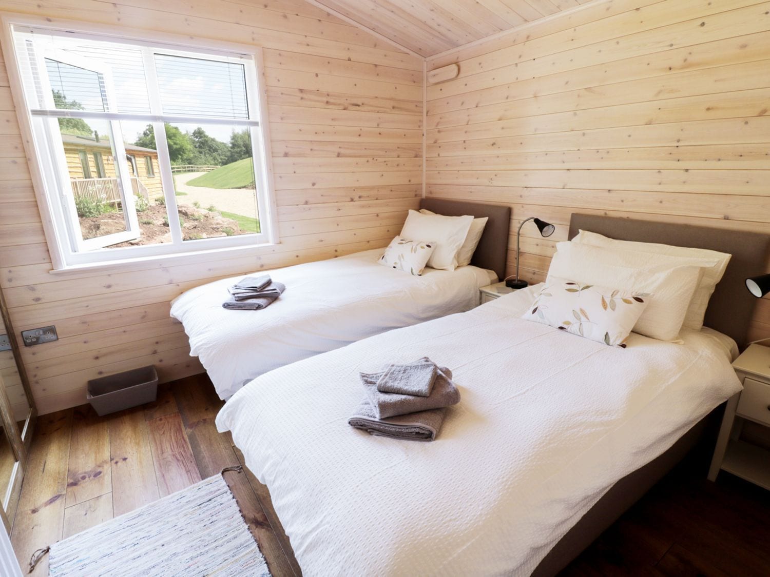 Una habitación con dos camas, una ventana y piso de madera.