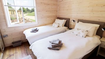 Una habitación con dos camas, una ventana y piso de madera.