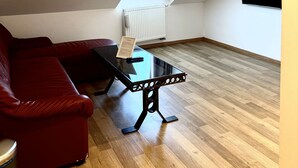 A room with a sloped ceiling, a red sofa, a small table, and a radiator. - Penzión a reštaurácia Raimund (Vysoké Tatry)