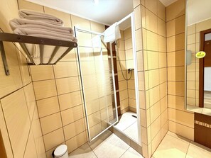 A bathroom with a glass shower enclosure, a towel rack, and a toilet. - Penzión a reštaurácia Raimund (Vysoké Tatry)