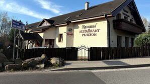 A building with a sign for 'Raimund Restaurant Penzion' and a directional sign for 'Nova Lesná Dolný Smokovec.' - Penzión a reštaurácia Raimund (Vysoké Tatry)
