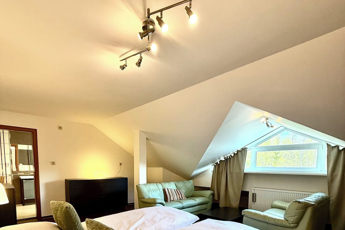 Un dormitorio con una cama grande, un sofá, un escritorio y una ventana con cortinas.