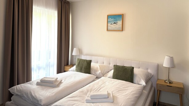 Una habitación de hotel con dos camas, un cuadro en la pared y una mesita de noche con una lámpara.