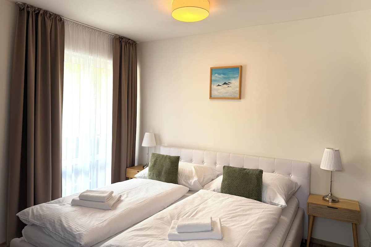 Una habitación de hotel con dos camas, un cuadro en la pared y una mesita de noche con una lámpara.