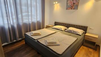 Een slaapkamer met een bed, gordijnen, een airconditioner, een nachtkastje en een wandlamp.