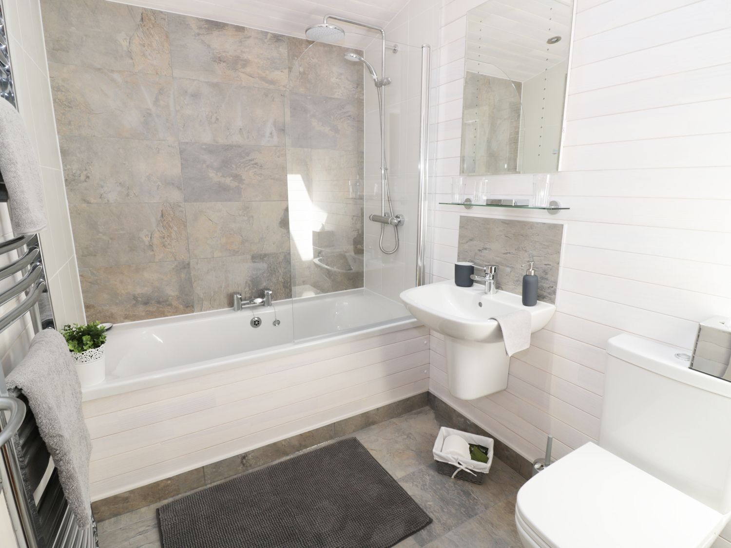 Un baño moderno con cabina de ducha de vidrio, un lavabo blanco y un inodoro.