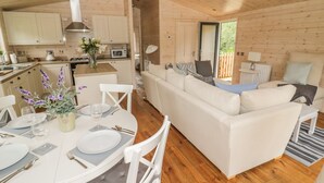 Interior acogedor de una cabaña con comedor, sofá blanco y suelo de madera.