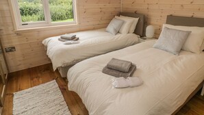 Una habitación con dos camas, una ventana y piso de madera.