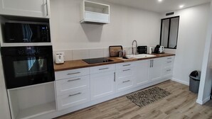 A modern kitchen with white cabinetry, a wooden countertop, a built-in microwave, a toaster, and a sink.