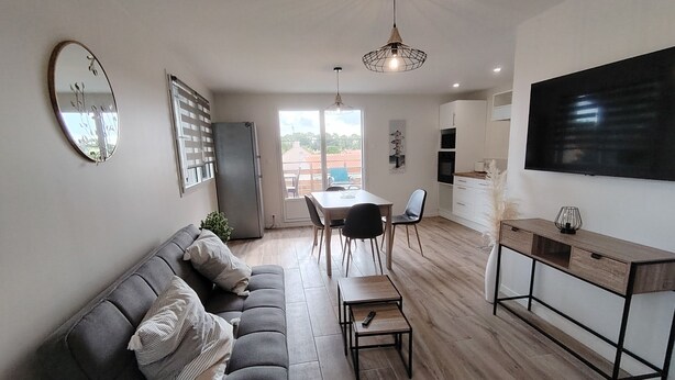 A modern living room with a sofa, dining table, chairs, and a TV.