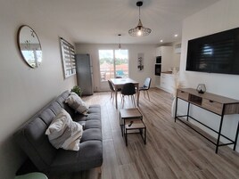 Un salon moderne comprenant un canapé, une table à manger, des chaises et un téléviseur.