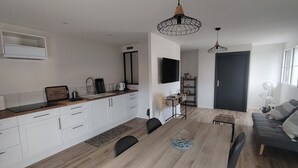 A modern kitchen with white cabinets, a wooden dining table, and black chairs.