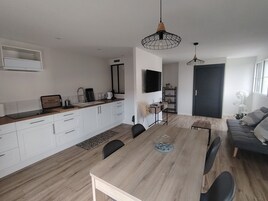 Une cuisine moderne avec des meubles blancs, une table à manger en bois et des chaises noires.