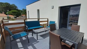 A deck with a table and chairs, a blue sofa, and a wicker chair.
