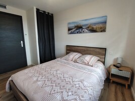 Une chambre à coucher avec un lit, un tableau, une table de chevet et une porte.