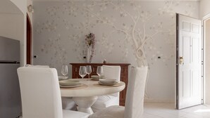 A dining area with a round table, white chairs, and a floral wall design. - Giglio Pool & Nature 15 mins to Pisa | Domio (Cascina)