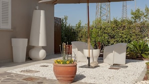 A patio area with a large umbrella, outdoor furniture, a potted plant, and a stone pathway. - Giglio Pool & Nature 15 mins to Pisa | Domio (Cascina)