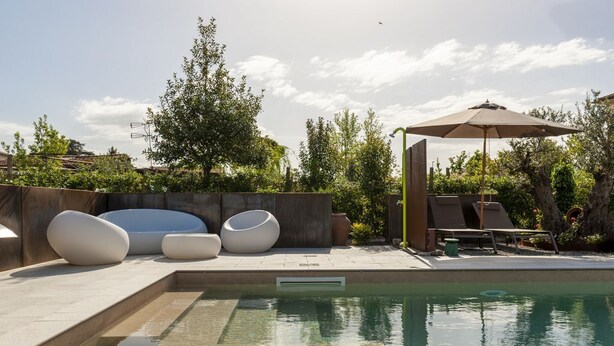 A swimming pool with modern seating and a pergola.