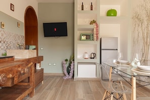 Uma cozinha moderna com televisão, móveis de madeira, uma mesa de jantar de vidro e micro-ondas.