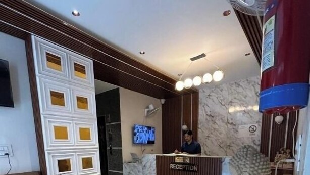 A reception desk with a marble wall, a statue, and a TV screen. - Namaste Haridwar By Oran Hotels (Haridwar)