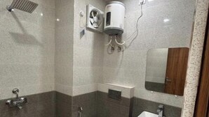 A bathroom with a shower, toilet, sink, and a ventilation unit. - Namaste Haridwar By Oran Hotels (Haridwar)