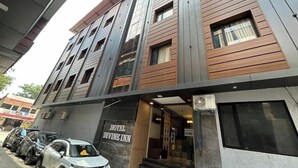 A multi-story hotel with a modern facade, a sign reading 'HOTEL DIVINE INN,' and a parking area with several cars. - Namaste Haridwar By Oran Hotels (Haridwar)