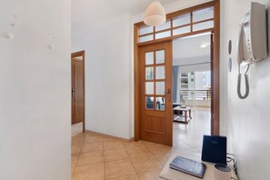 A hallway with a wooden door, a wall-mounted telephone, and a laptop on a table. - Apartment 'Rei  3º T' with Balcony, Wi-Fi and Air Conditioning (Quarteira)