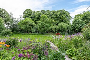 Un jardin où l’on trouve une grande variété de fleurs et d’arbres.