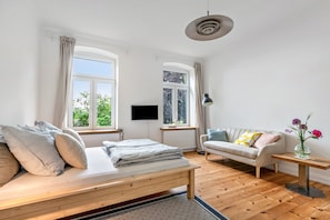 Une chambre moderne équipée d’un lit, de deux canapés, d’une télévision et de grandes fenêtres.