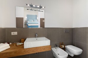 Un bany modern amb un gran mànec rectangular, un vàter, i un mirall sobre el mànec.