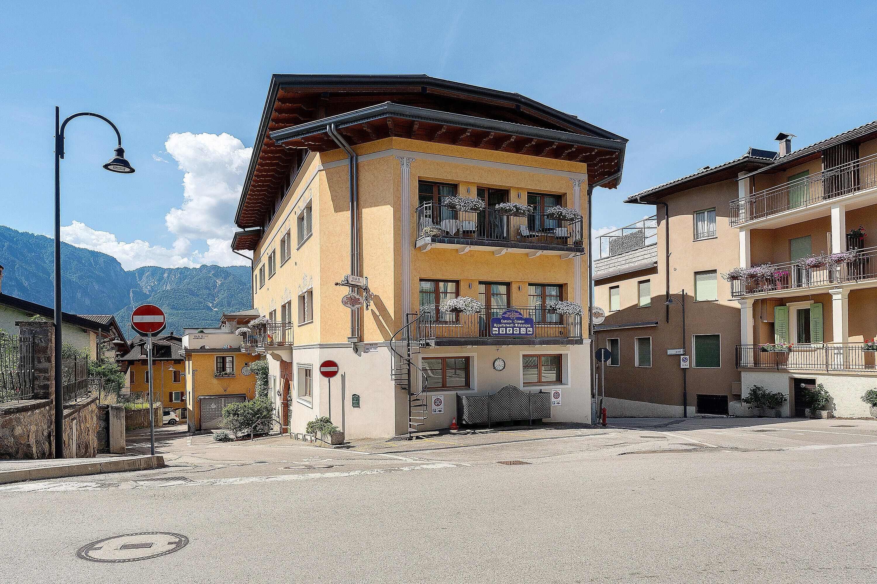 Un immeuble à plusieurs étages, doté de balcons, avec une entrée bien visible et un ciel dégagé.