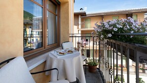 A balcony with a table set for two, a chair, and a potted plant.
