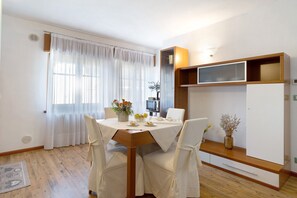 A dining area with a table set for two, a microwave, and a cabinet with a shelf. - Apartment 'You An Me' with Mountain View, Balcony and Wi-Fi (Levico Terme)